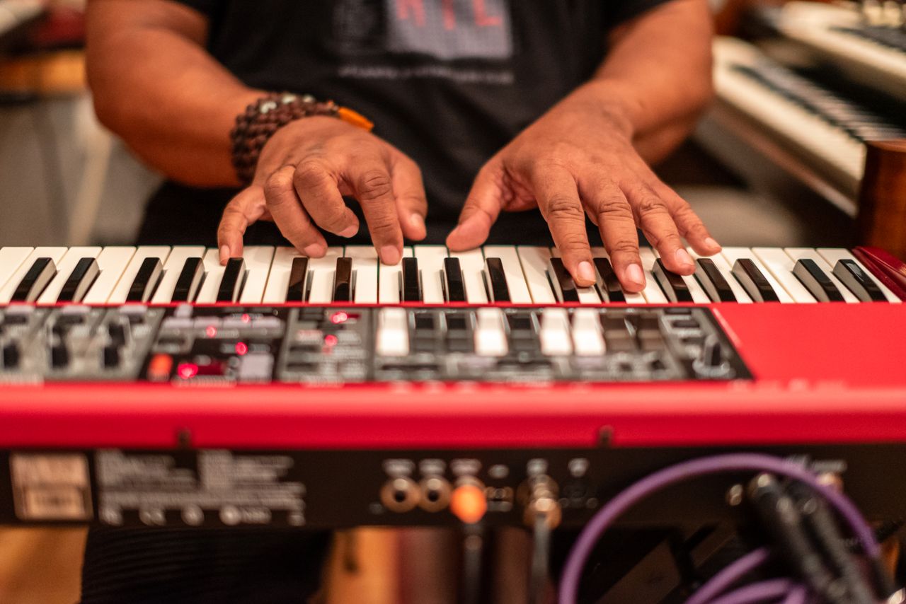 Close-up of musician's hands playing a keyboard in a recording studio.